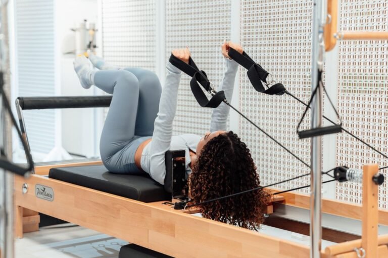 a woman is exercising on reformer pilates mashine